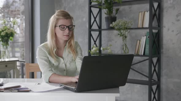 Happy Calm Woman Holds Hands Behind Head Feeling Relieved Relaxes and Sits at Home Office with