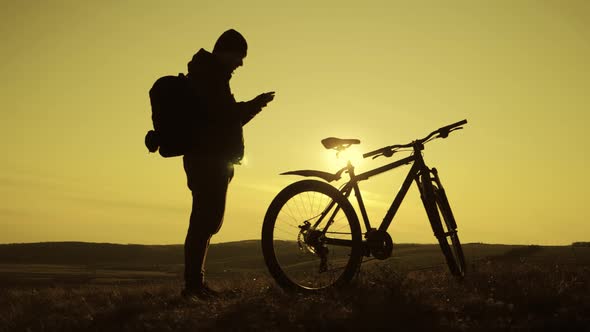Silhouette of the Mountain Bicycle Rider on the Hill with Bike at Sunset. Sport, Travel and Active