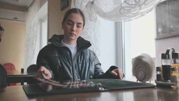 A Young Girl Sits in a Cafe and Opens the Menu