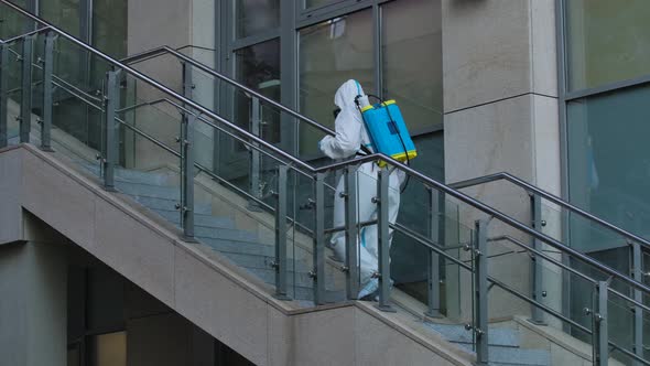 Disinfector in a Protective Suit Treats the Territory of City Streets, Sprays an Antibacterial