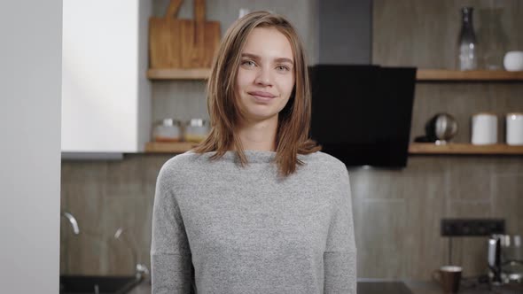 Portrait of a Young Smiling Girl with Short Brown Hair Standing in the Middle of a Room