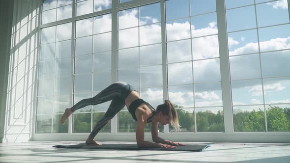 Young Female Is Doing Yoga in a White Room Filled with Light, the Girl Performs Yoga Stands and