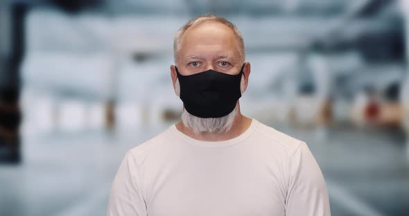 Adult Man on a Protective Mask Looks at the Camera, Portrait of a Gray-haired Man on a Blurry