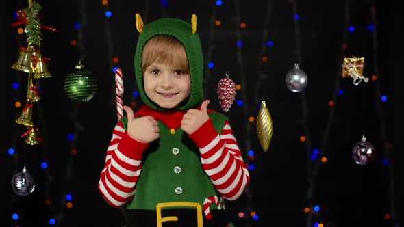 Teen Kid Girl in Christmas Elf Santa Claus Helper Costume Pointing at Something Showing Thumbs Up