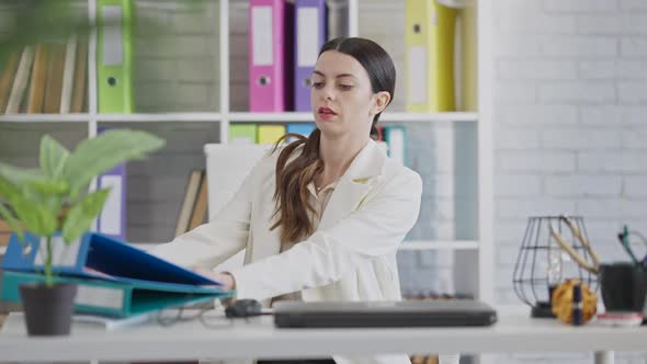 Portrait of Serious Beautiful Young Businesswoman Sitting in Office Opening Laptop on Slow Motion