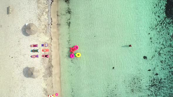 Aerial view of people lying in yoga pose on on the with inflatables on beach.