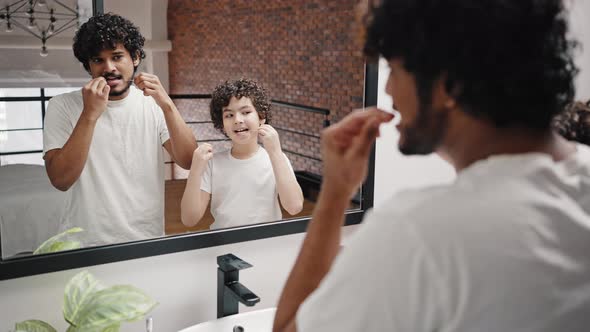 Father and Son Clean Teeth with Dental Floss in Bathroom