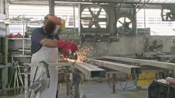 Slow motion of a worker using metal grinder with sparks flying at a metal shop