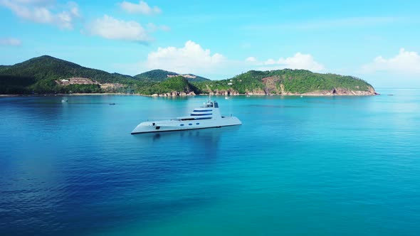 Luxurious big yacht anchoring on calm blue turquoise bay near shore of tropical island with green ve