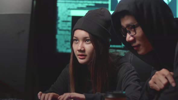 Young Asian Couple Hackers Using Computer Hacking, Code On Multiple Computer Screens