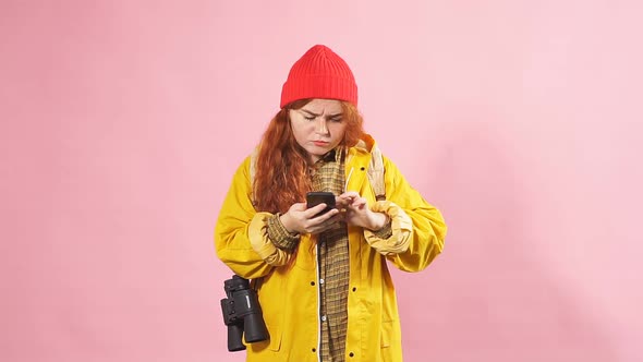 Portrait of a Red-haired Tourist Girl Using a Mobile Phone To View a Map.