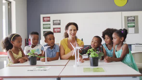 Video of happy caucasian female teacher and class of diverse pupils studying ecology in classroom