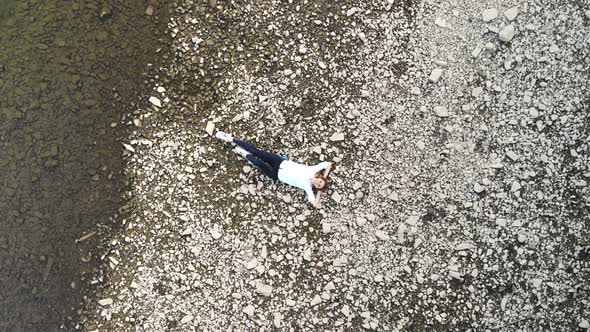 Aerial Top View of Happy Woman Lying on Beach of Mountains River Enjoying Nature in White with Hands