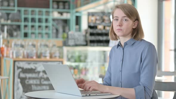 Young Woman with Laptop Pointing Towards Camera