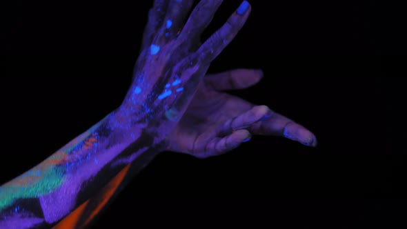 Closeup of a Woman with Ultraviolet Drawings on Her Hands She Moves Her Fingers