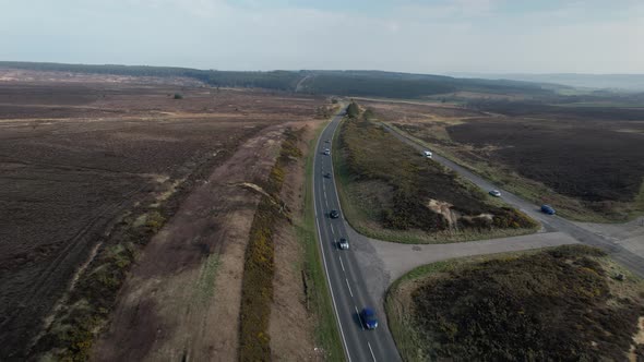 Aerial view above vehicles driving long straight road through rural Goathland North Yorkshire moorla