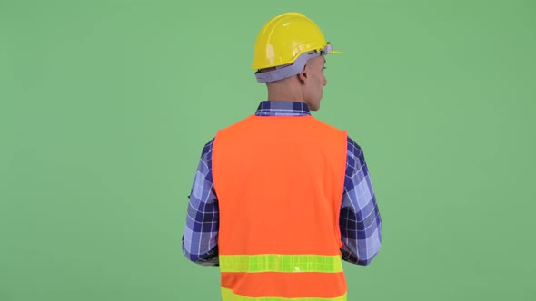 Rear View of Multi Ethnic Man Construction Worker Holding Clipboard and Looking Around