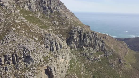 scenic aerial drone view ascending over Table Mountain with its steep majestic rocky sandstone cliff