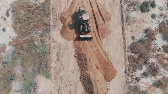 Aerial Top Down View Of Earth Mover Flattening Material On Ground In Pakistan