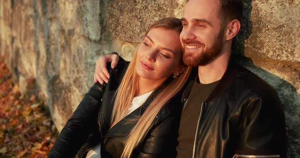 Portrait of Happy Romantic Couple in Love Relaxing in Embraces at Park's Wall