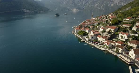 Aerial shot of the Bay of Kotor and Perast. slow push in with mountains in the distance on a sunny d