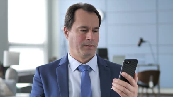 Businessman Reacting to Loss While Using Smartphone