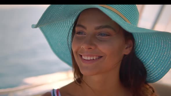 Portrait of Pretty Smiling Tanned Woman in Blue Straw Hat Enjoying the Sun and Breeze at Sea Boat