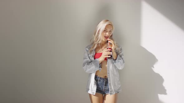 Young Blonde Model in Denim Posing in Studio with Soda Drink