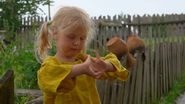 Charming Blond Farm Girl Standing in the Rain Near the Wooden Village Fence