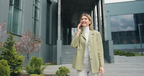 Caucasian Beautiful Female After Work, Walking in City and Speaking on Smartphone.