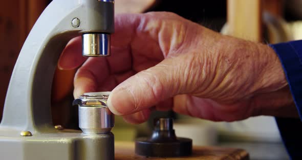 Horologist repairing a watch on a machine