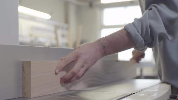 Carpenter Trimming Natural Wood Board on Jointer at Furniture Making Workshop