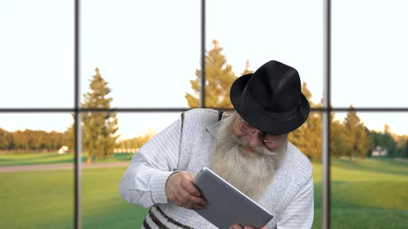 Senior Man Playing Game on Digital Tablet.