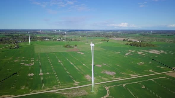 Aerial view of wind turbines generating renewable energy in the wind farm, sunny spring day, low fly