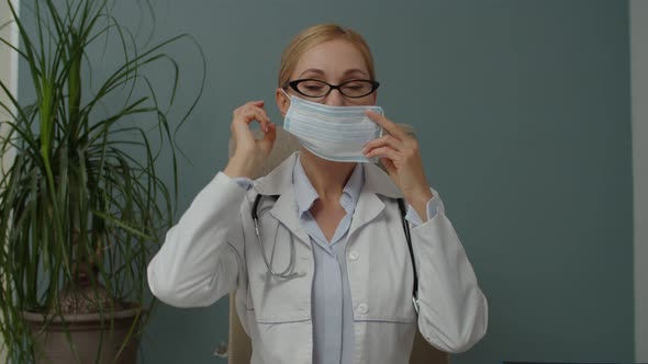 Female Doctor Putting on Face Mask for Protection Coronavirus Indoors