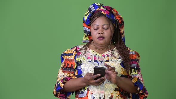 Overweight Beautiful African Woman Wearing Traditional Clothing Against Green Background