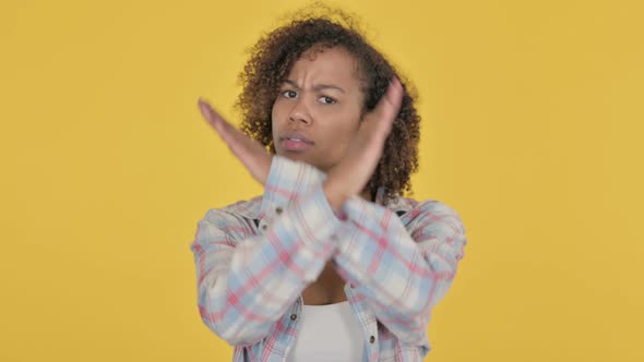 Young African Woman Showing No Sign By Arm Gesture on Yellow Background