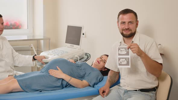 The Father Holds a Picture of the Unborn Child in His Hands