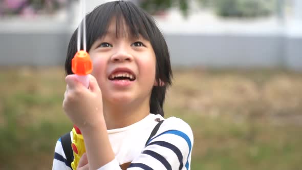 Cute Asian Child Playing With Water Gun In The Summer