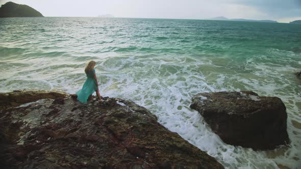 Woman Meditates Relaxes on a Rock Reef Hill in Stormy Morning Rain Cloudy Sea