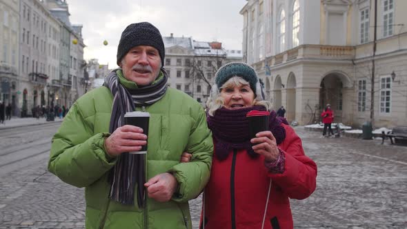 Senior Old Tourists Grandmother Grandfather Walking Drinking Hot Drink Mulled Wine in City Center