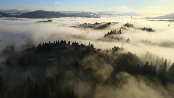 Aerial View of a Village Houses on Hill Top in Autumn Foggy Mountains at Sunrise