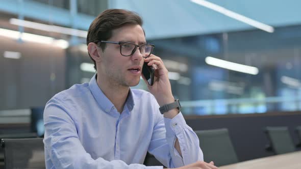 Young Man Talking on Phone at Work