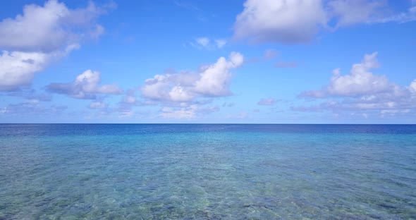 Wide angle flying travel shot of a white paradise beach and blue water background in vibrant 4K