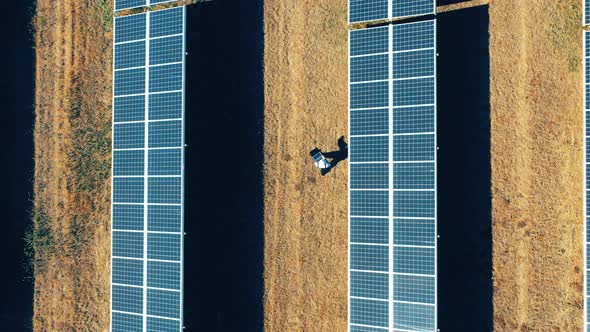 Top View of a Repairman Walking Among Solar Panels