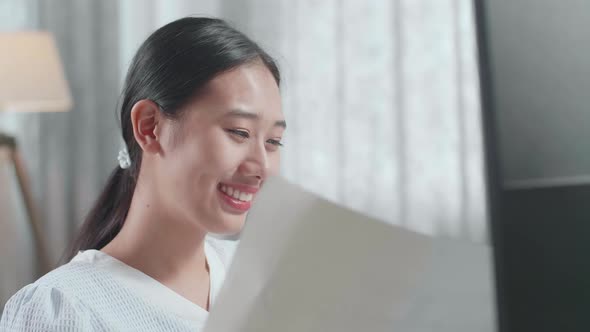 Asian Woman Engineer Looking At The Blueprint While Working On A Desktop At Home