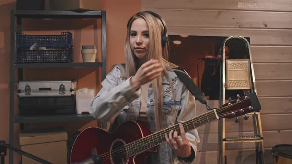 Blonde Female Guitarist In Headphones Playing Guitar