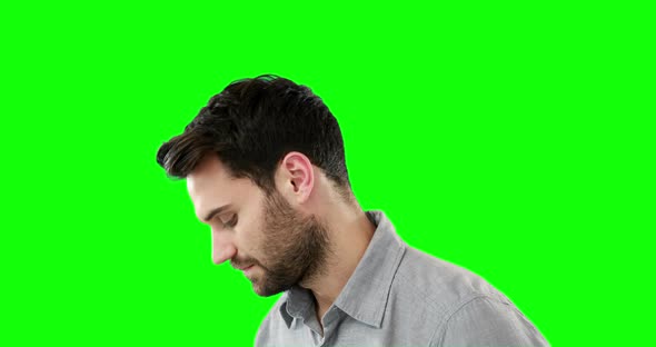 Thoughtful man standing against green background