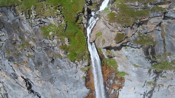 Aerial slow motion: drone flying over scenic waterfall and mountain stream on the italian Alps
