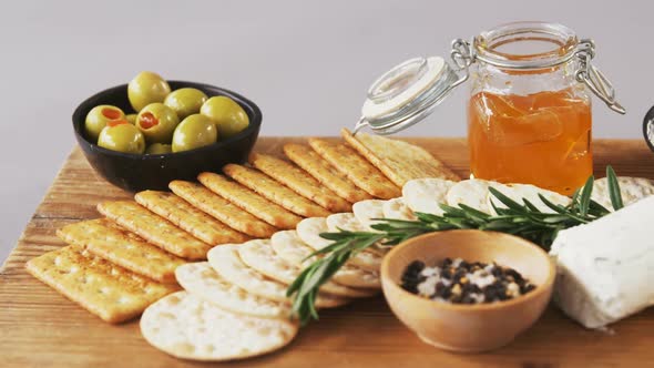 Bowl of green olives, spices, crispy biscuits, jam, rosemary herb, cheese and walnuts